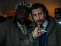 Aaron Taylor-Johnson und Brian Tyree Henry, Teil der Besetzung von Bullet Train, blicken ernst in die Kamera, während sie sich auf einem Zugabteil gegenüberstehen.