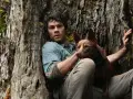 Ein Mann und sein Hund ruhen sich an einem Baum aus. Ihre Liebe ist ein Licht gegen die drohenden Monster der Welt.