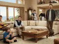 Die Besetzung von Two and a Half Men in einem Wohnzimmer. Ein Mann spielt Gitarre, ein Junge isst Pizza, ein anderer Mann sitzt nachdenklich da. Zwei Frauen in Dienstkleidung und ein Mann stehen im Hintergrund.