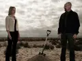 Die Besetzung von Breaking Bad: Walter und Skyler stehen in der Wüste, eine Schaufel liegt neben einem frisch aufgeworfenen Erdwall.