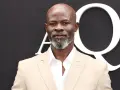 Djimon Hounsou, bekannt aus vielen Filmen, trägt einen hellbeigen Anzug und ein weißes Hemd.