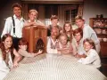 Die Besetzung von Die Waltons versammelt sich um ein Radio. Die Familie lächelt fröhlich in die Kamera.