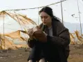 Eine junge Frau liest in einem alten Buch, umgeben von verwitterten Netzen. Ein Moment der Ruhe in der Welt von Oderbruch Staffel 3.
