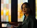 Tessa Thompson in einem grünen Mantel, mit einem Heft in der Hand, vor einem bunten Fenster. Ein Blick auf ihre Rolle in Filmen von Tessa Thompson.