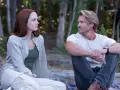 Ein Mann und eine Frau sitzen im Wald und schauen sich an. Sie sind Charaktere aus Sullivan's Crossing Staffel 4.