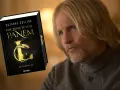 Ein Mann mit langen blonden Haaren und Bart, der an die Besetzung von "Die Tribute von Panem" erinnert, blickt nachdenklich auf das Buch "Die Tribute von Panem".