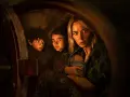 Die Besetzung von A Quiet Place: Eine Mutter hält ihr Baby, während ihre Kinder ängstlich in einem dunklen Versteck kauern.