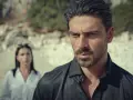 Michele Morrone, bekannt aus Filmen wie "365 Days", blickt nachdenklich in die Ferne, während eine Frau im Hintergrund steht.