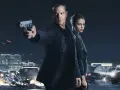 Jason Bourne und Alicia Vikander in Aktion. Ein Auto brennt, während Jason eine Waffe abfeuert. Die besetzung von Jason Bourne ist bereit für den Kampf.