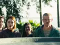Menschen stehen dicht gedrängt, einige lächeln, andere blicken ernst. Verschiedene Arten von Freundlichkeit spiegeln sich in ihren Gesichtern.