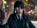 Wednesday Addams hält mit einer Pinzette ein künstliches Auge vor ihrem Gesicht. Ein Blick auf die kommende Staffel 2 von Wednesday.