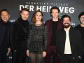 Das Ensemble des Films "Der heimweg" posiert lächelnd vor dem Banner.