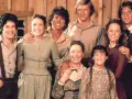 Die Besetzung von Unsere kleine Farm: Eine glückliche Familie posiert vor einer Holzwand.