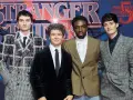 Die Besetzung von Stranger Things posiert vor dem Logo der Serie.