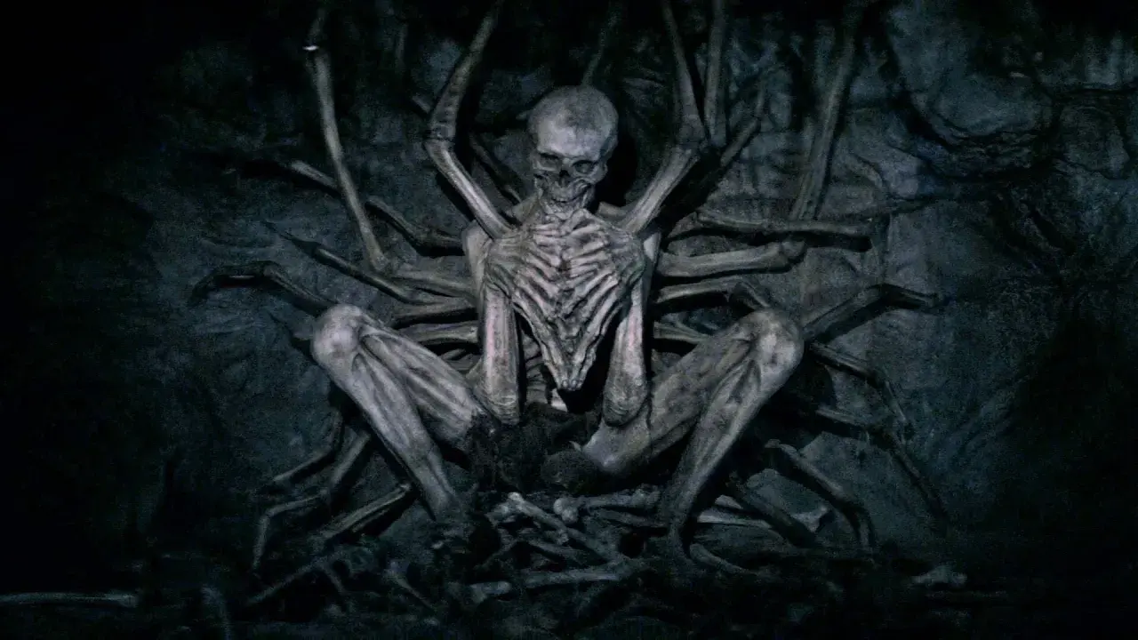 Ein skelettartiges Wesen, der leere Mann, sitzt in einer dunklen Höhle, umgeben von knochigen Gliedmaßen.