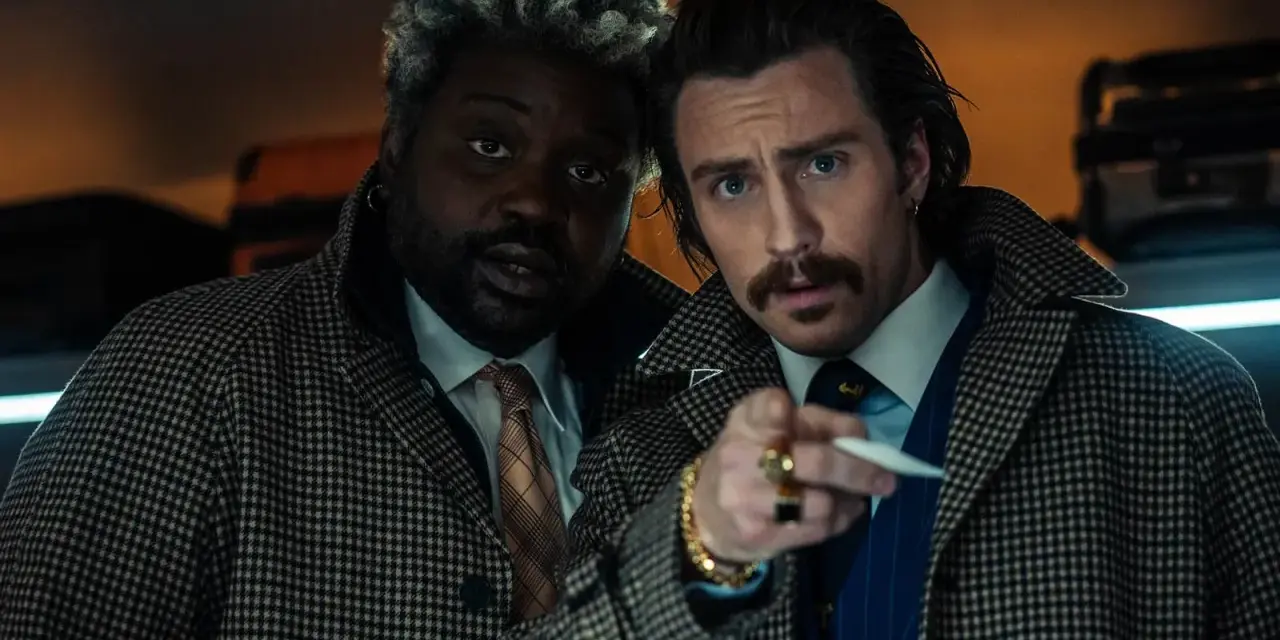 Aaron Taylor-Johnson und Brian Tyree Henry, Teil der Besetzung von Bullet Train, blicken ernst in die Kamera, während sie sich auf einem Zugabteil gegenüberstehen.