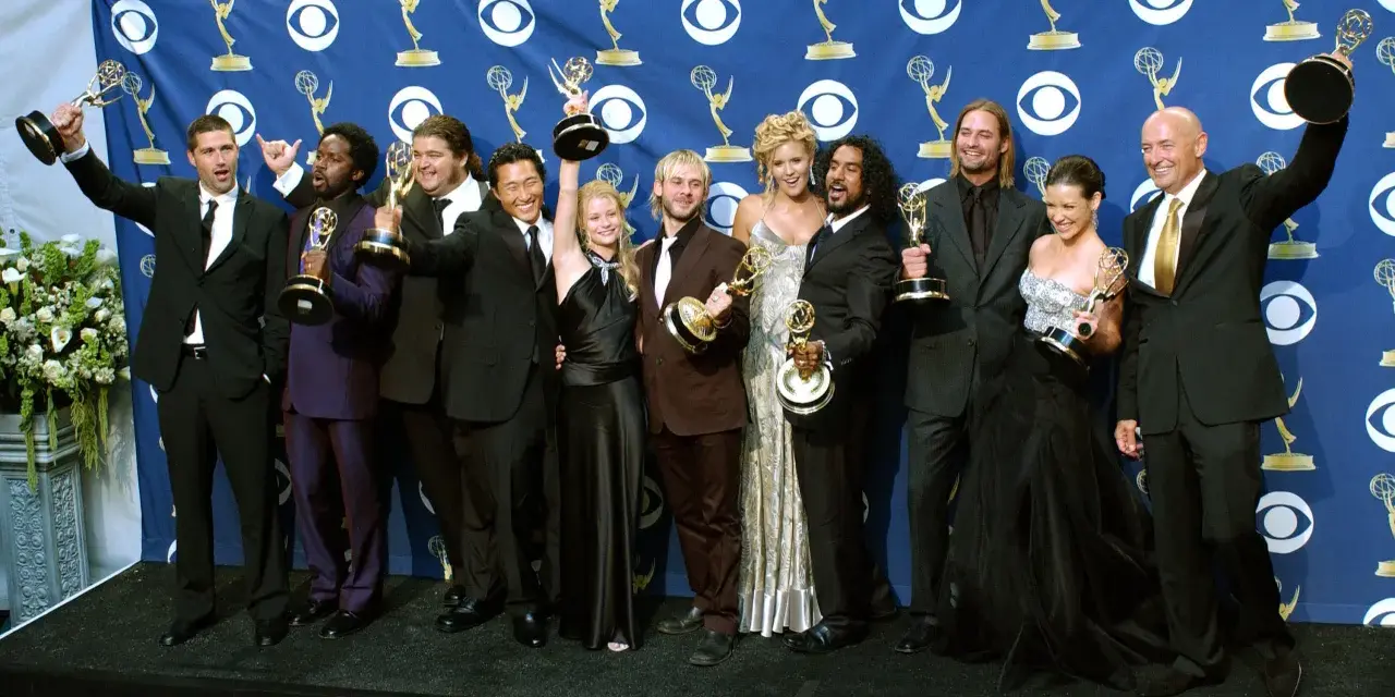 Die Besetzung von Lost feiert Emmy-Erfolge. Die Schauspieler posieren mit ihren Trophäen vor einem blauen Banner mit dem CBS-Logo.