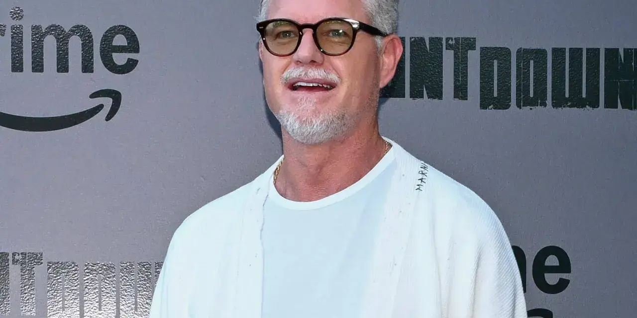 Eric Dane, bekannt für seine Rollen in Filmen und Serien, trägt eine Brille und ein weißes Outfit vor einem grauen Hintergrund mit dem Amazon Prime Logo.