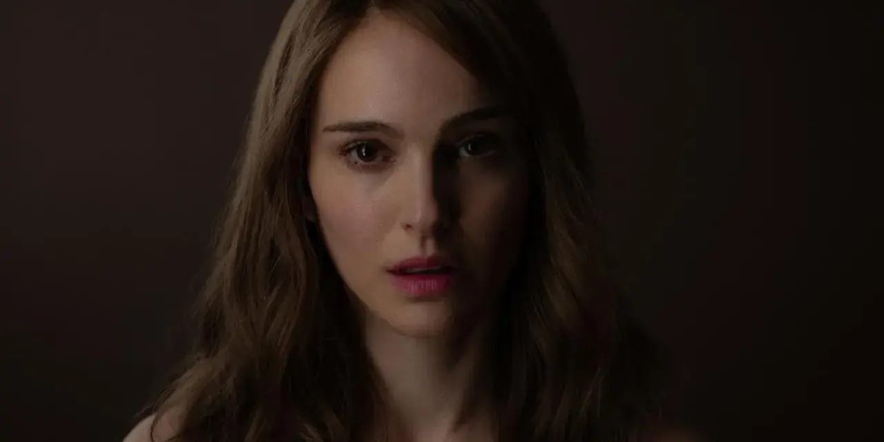 Natalie Portman, bekannt aus vielen Filmen, blickt nachdenklich in die Kamera. Ihr Gesicht ist im Schatten, nur ihre Augen und Lippen sind beleuchtet.
