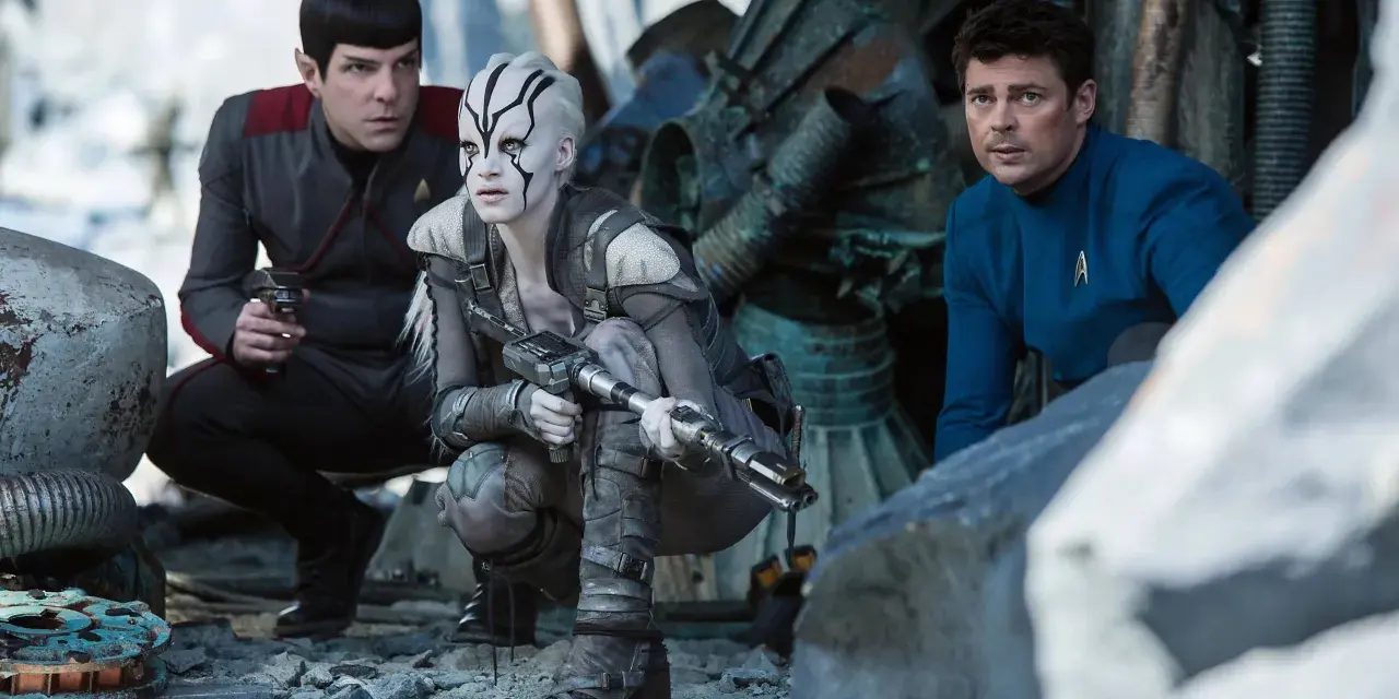 Die Besetzung von Star Trek 2009: Spock, eine Kriegerin mit Kriegsbemalung und Dr. McCoy kauern im Trümmerfeld.