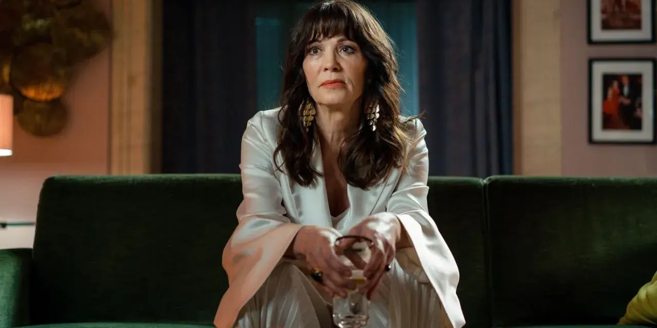 Iris Berben in einem eleganten Outfit, nachdenklich auf einem grünen Sofa sitzend. Ein Blick, der an ihre vielen Filme erinnert.