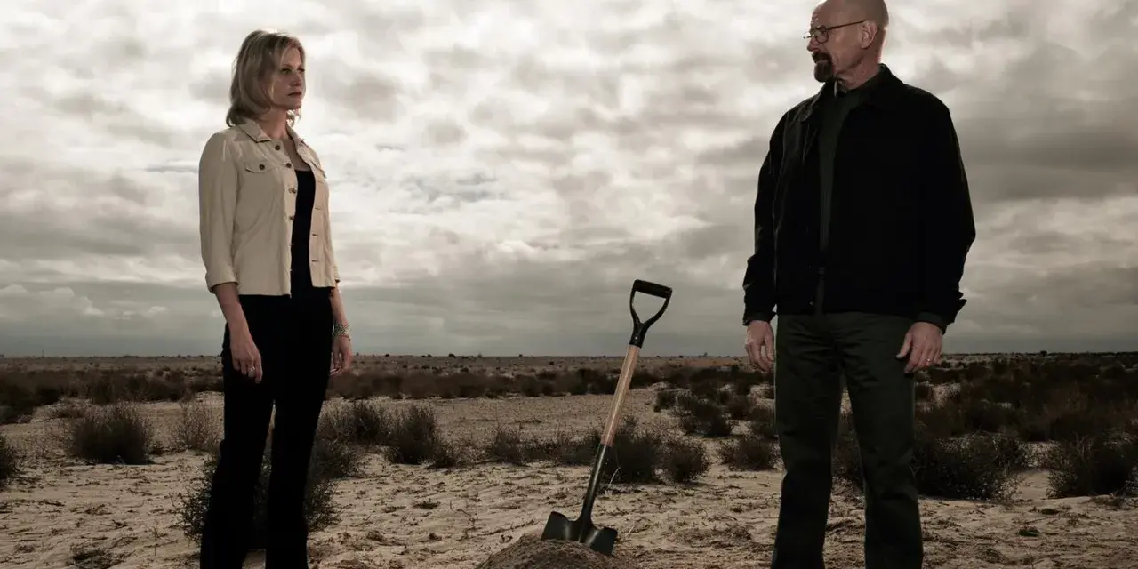 Die Besetzung von Breaking Bad: Walter und Skyler stehen in der Wüste, eine Schaufel liegt neben einem frisch aufgeworfenen Erdwall.