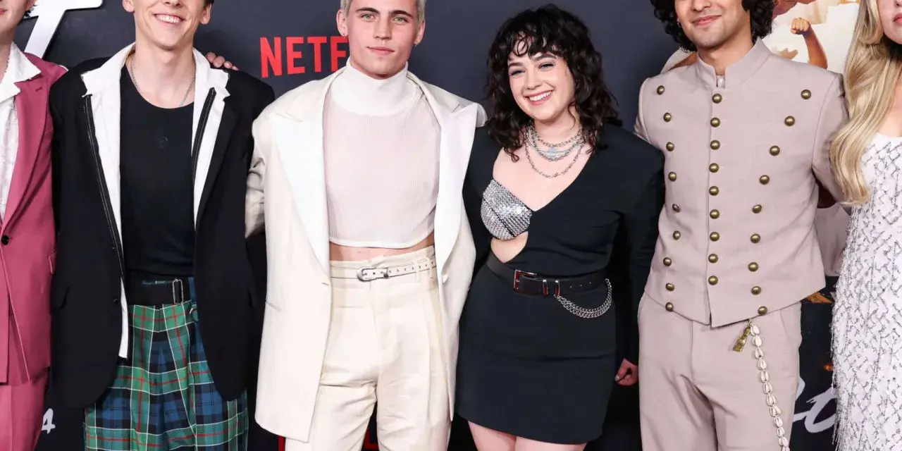 Vier junge Darsteller von Cobra Kai posieren lächelnd auf einem roten Teppich.