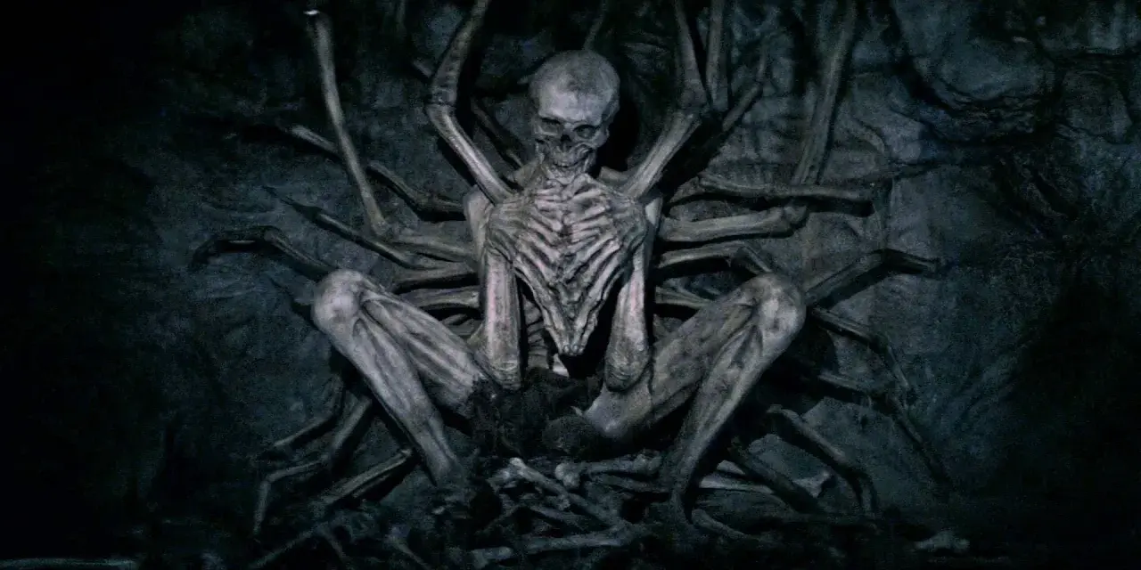 Ein skelettartiges Wesen, der leere Mann, sitzt in einer dunklen Höhle, umgeben von knochigen Gliedmaßen.