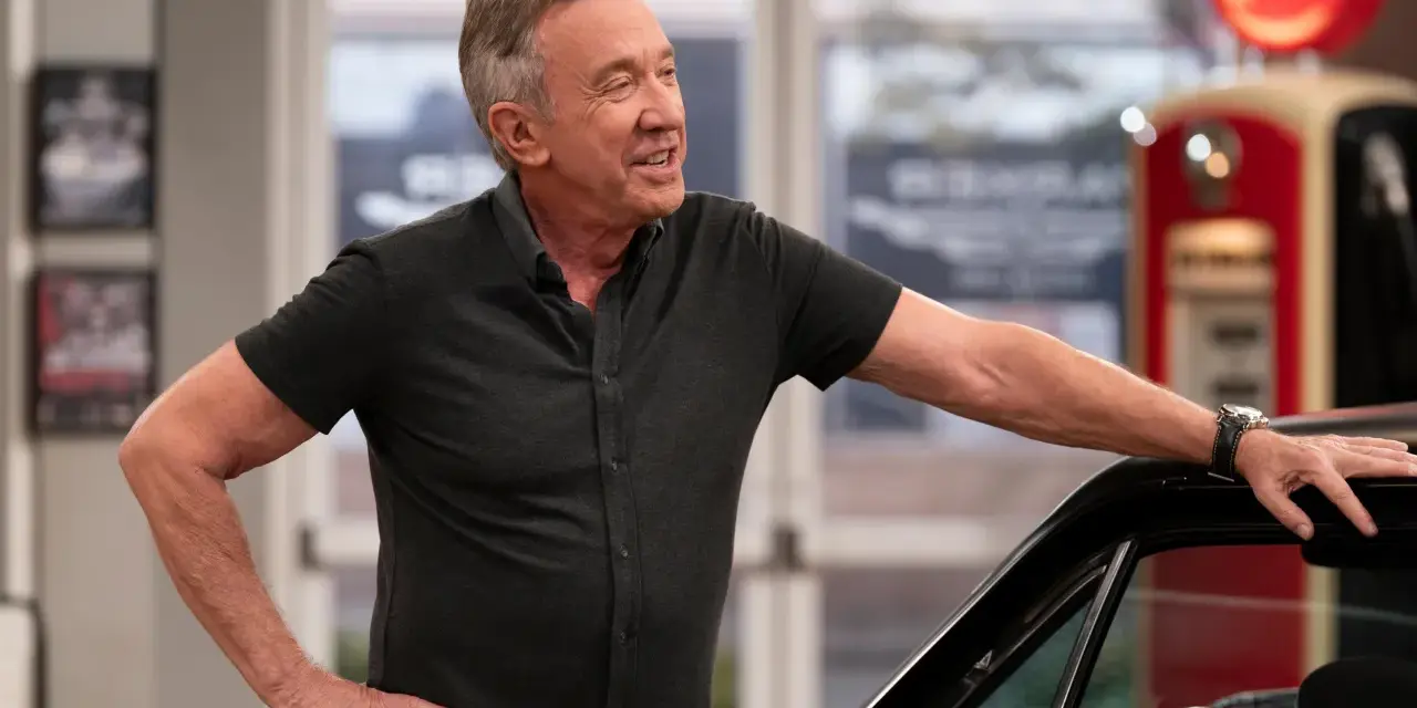 Tim Allen, bekannt für seine Filme und Serien, lehnt lässig an einem Auto. Im Hintergrund eine alte Zapfsäule.