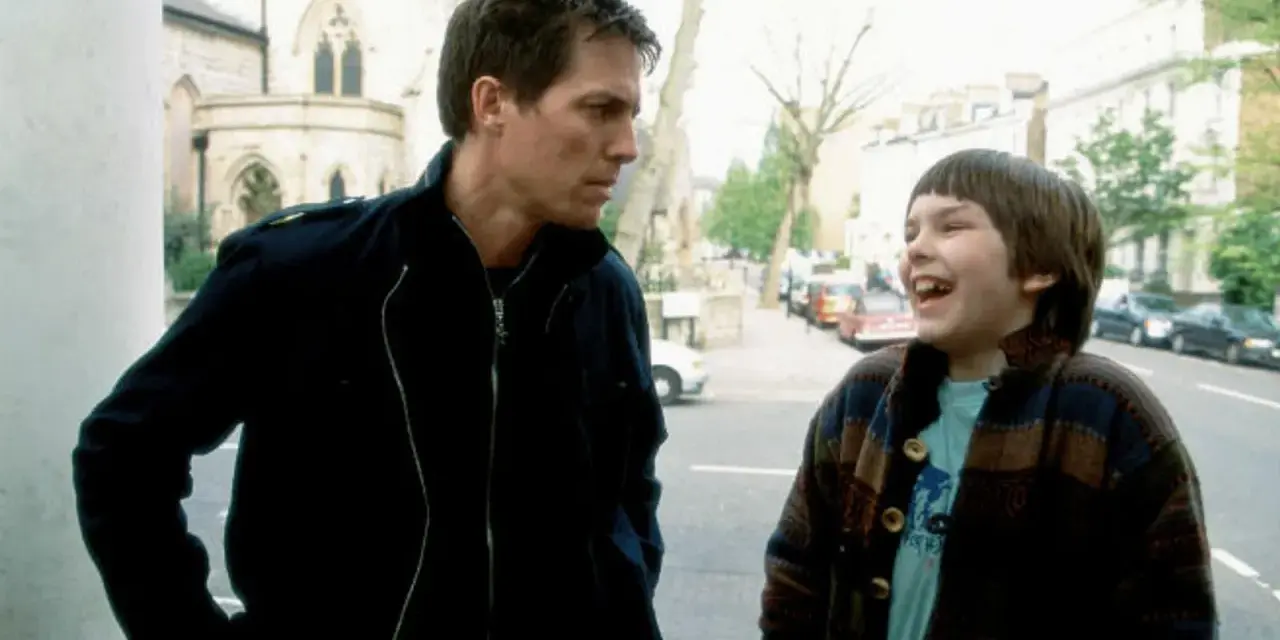 Nicholas Hoult lacht mit einem Mann auf der Straße. Ein Ausschnitt aus seinen Filmen und Serien.