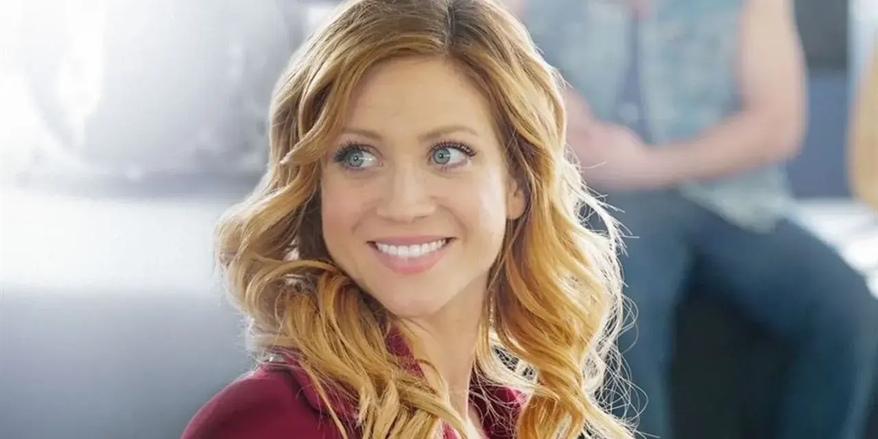 Brittany Snow lächelt in einem roten Blazer. Ein Blick auf ihre Rolle in Filmen von Brittany Snow.