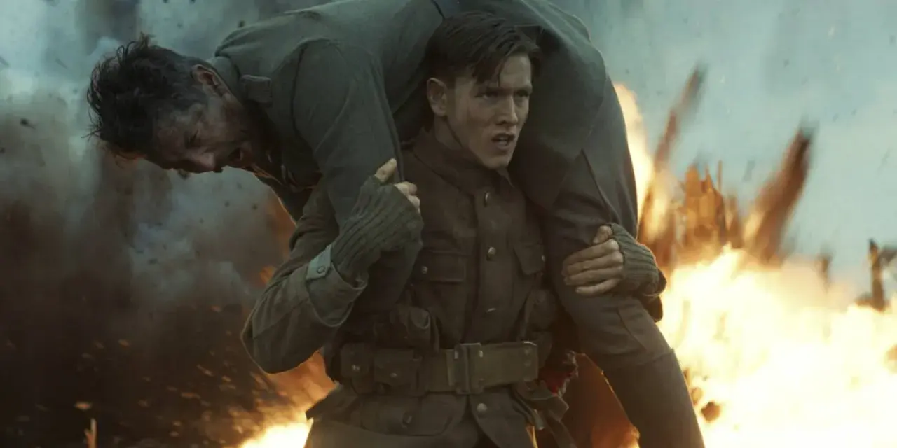 Harris Dickinson trägt einen verwundeten Kameraden durch Explosionen. Ein dramatischer Moment aus seinen Filmen.