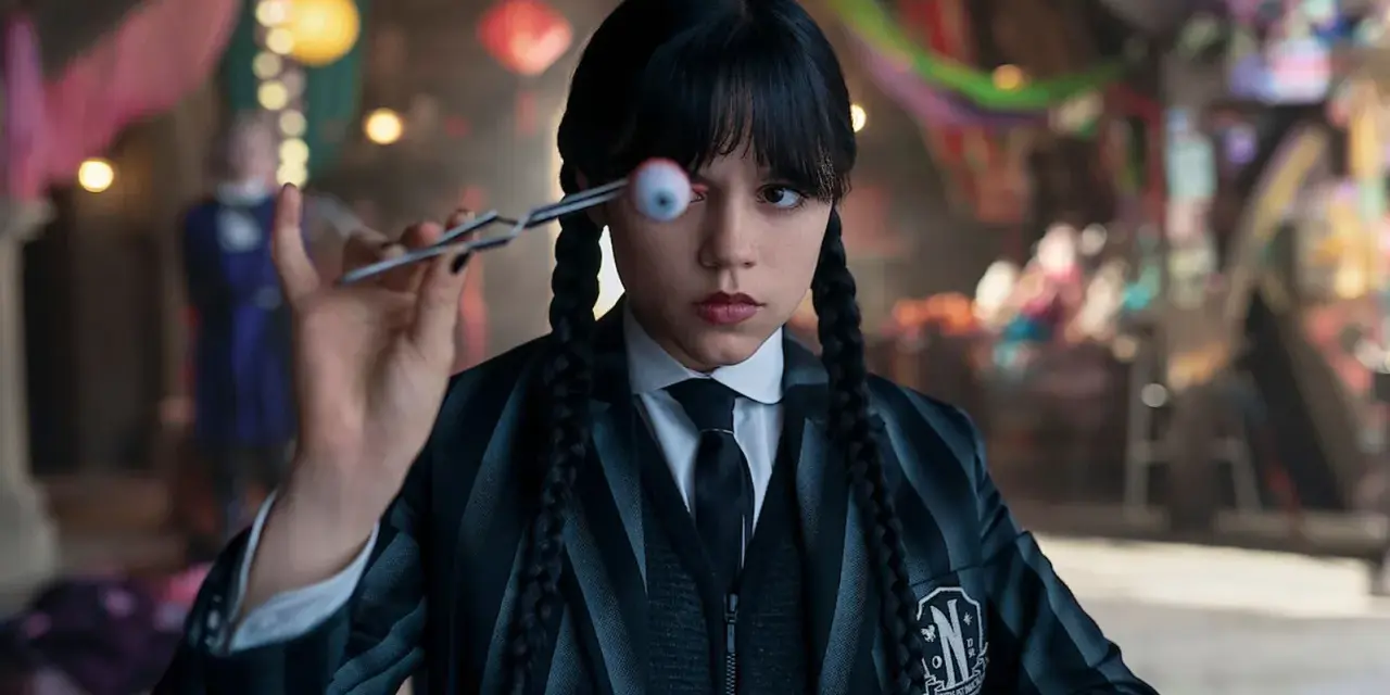 Wednesday Addams hält mit einer Pinzette ein künstliches Auge vor ihrem Gesicht. Ein Blick auf die kommende Staffel 2 von Wednesday.