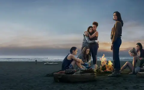 Die Gruppe von Mädchen am Strand bei einem Lagerfeuer. Die Stimmung ist nachdenklich, wie in "The Wilds Staffel 3".