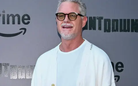 Eric Dane, bekannt für seine Rollen in Filmen und Serien, trägt eine Brille und ein weißes Outfit vor einem grauen Hintergrund mit dem Amazon Prime Logo.