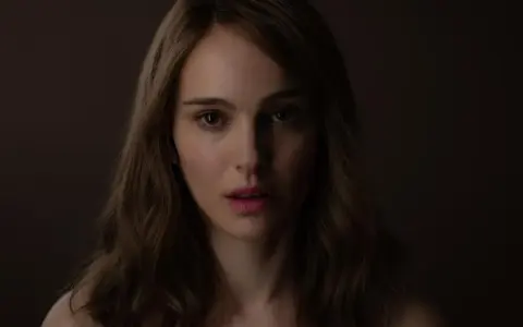 Natalie Portman, bekannt aus vielen Filmen, blickt nachdenklich in die Kamera. Ihr Gesicht ist im Schatten, nur ihre Augen und Lippen sind beleuchtet.