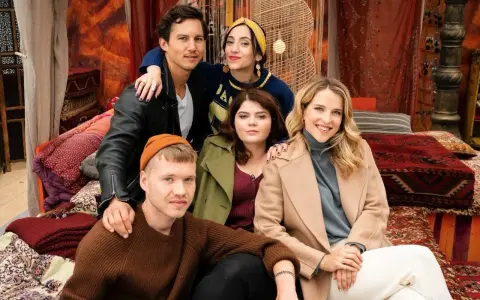 Die Besetzung von "Damaged" posiert in einer orientalisch inspirierten Kulisse. Fünf junge Menschen, drei Frauen und zwei Männer, sitzen und lehnen sich aneinander.
