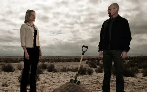 Die Besetzung von Breaking Bad: Walter und Skyler stehen in der Wüste, eine Schaufel liegt neben einem frisch aufgeworfenen Erdwall.