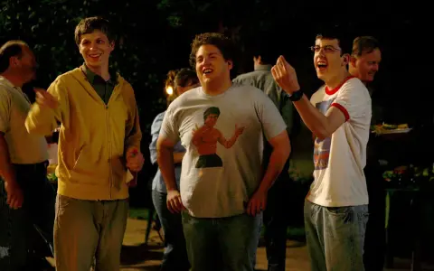 Die Besetzung von Superbad feiert eine Party. Michael Cera, Jonah Hill mit Bruce Lee T-Shirt und Christopher Mintz-Plasse lachen ausgelassen.