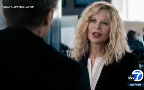 Meg Ryan spricht mit einem Mann, während im Hintergrund Menschen sitzen. Was passiert später?