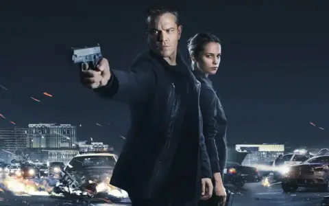 Jason Bourne und Alicia Vikander in Aktion. Ein Auto brennt, während Jason eine Waffe abfeuert. Die besetzung von Jason Bourne ist bereit für den Kampf.
