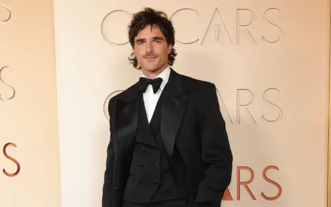 Jacob Elordi in einem schwarzen Smoking vor dem Oscars-Logo. Seine Filme und Serien sind ein Muss für Fans.