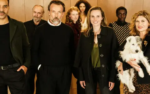Ensemble der Fernsehserie "Besetzung von Berlin" posiert lächelnd mit einem Hund.