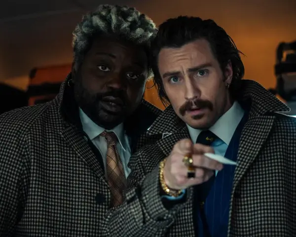 Aaron Taylor-Johnson und Brian Tyree Henry, Teil der Besetzung von Bullet Train, blicken ernst in die Kamera, während sie sich auf einem Zugabteil gegenüberstehen.