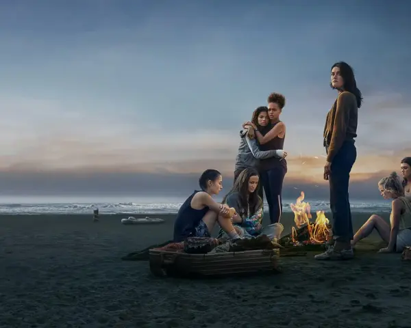 Die Gruppe von Mädchen am Strand bei einem Lagerfeuer. Die Stimmung ist nachdenklich, wie in "The Wilds Staffel 3".