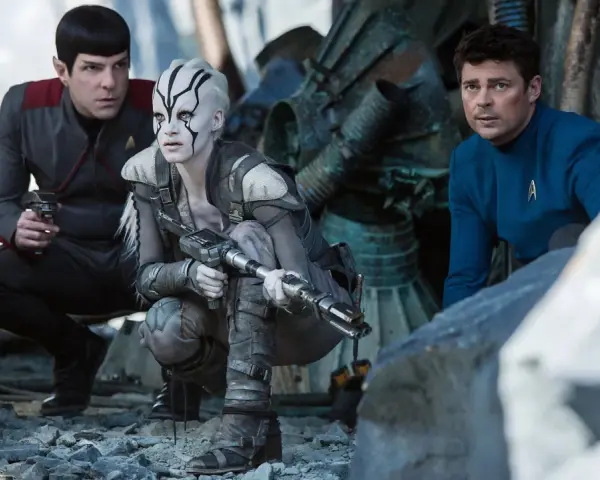 Die Besetzung von Star Trek 2009: Spock, eine Kriegerin mit Kriegsbemalung und Dr. McCoy kauern im Trümmerfeld.