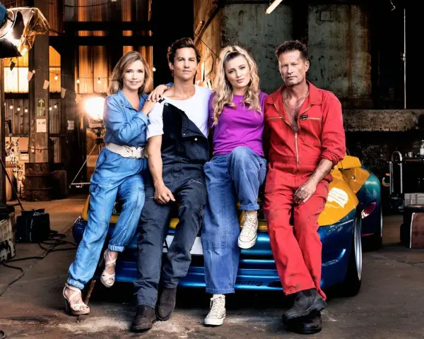 Die Besetzung von Manta Manta – Zweiter Teil: Til Schweiger, Tina Rönnau, Luna Schweiger und Moritz Bleibtreu posieren vor einem Auto in einer Werkstatt.