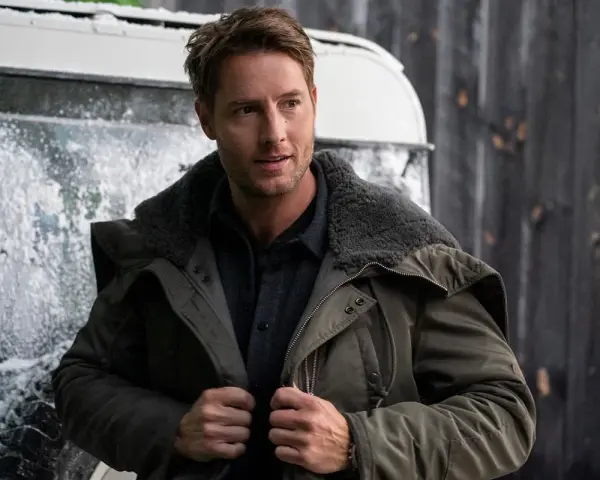 Mann in Winterjacke, inspiriert von "The Noel Diary", steht vor einer verschneiten Kulisse.