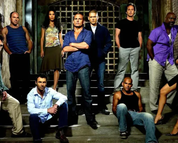 Die Hauptbesetzung von Prison Break posiert auf Treppen vor einem Gittertor.