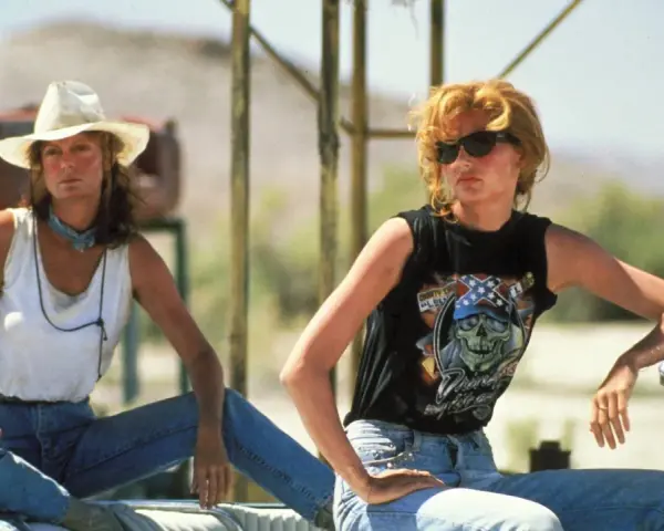 Die besetzung von Thelma & Louise: Geena Davis mit Cowboyhut und weißem Top, Geena Davis mit Sonnenbrille und schwarzem Shirt mit Totenkopf.